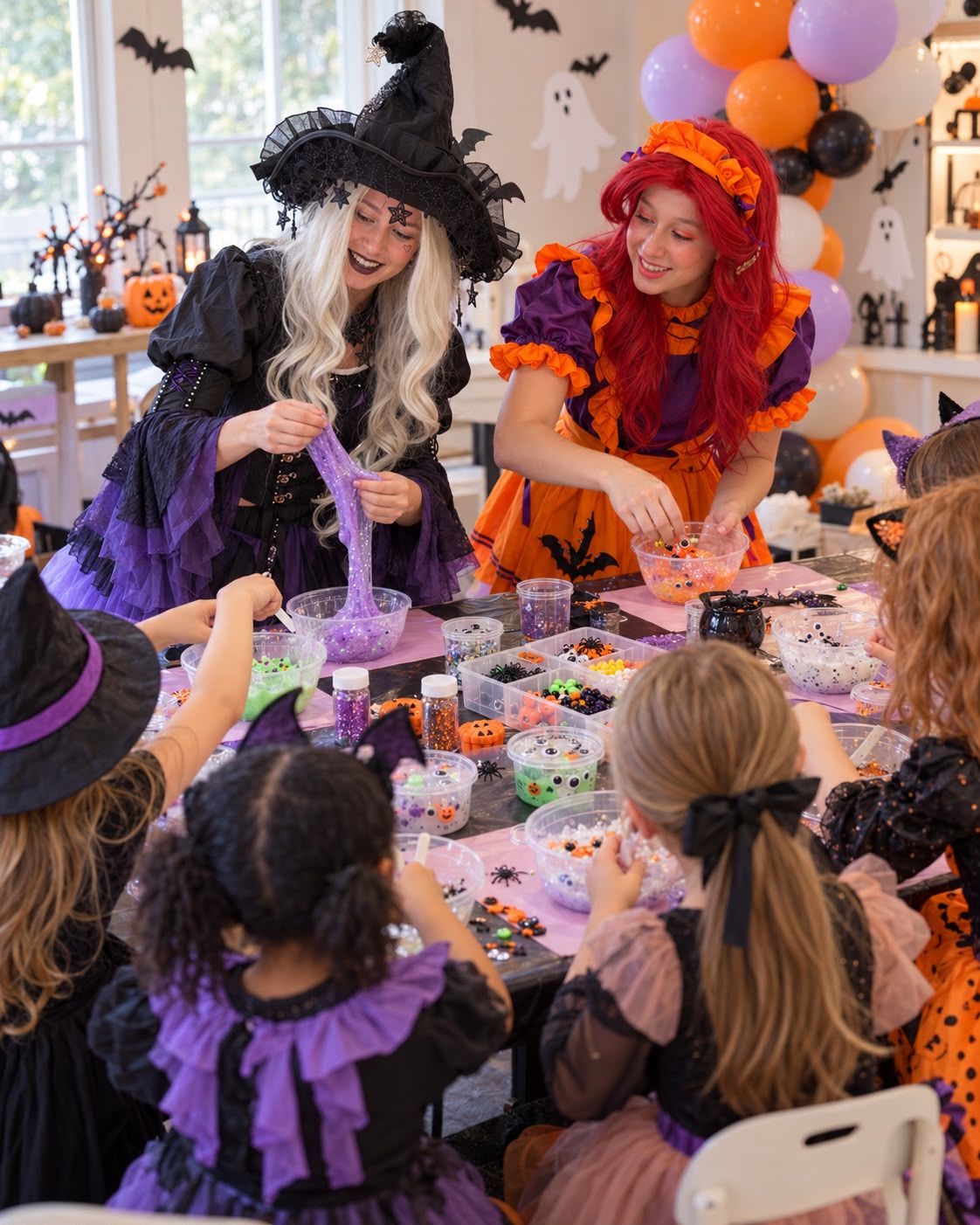 Two witches stretch purple glitter slime and add googly eyes at a long table of kids making Halloween slime